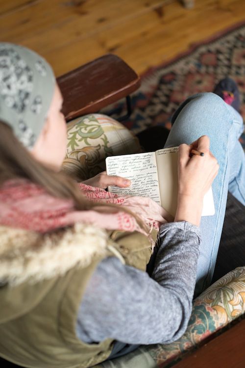 Woman writing in a journal, focus on the journal