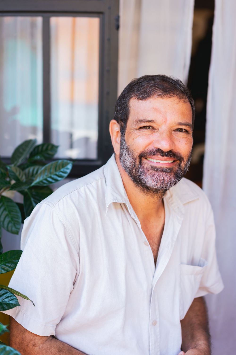 Middle-aged hispanic gentleman with beard and a white shirt looking at camera