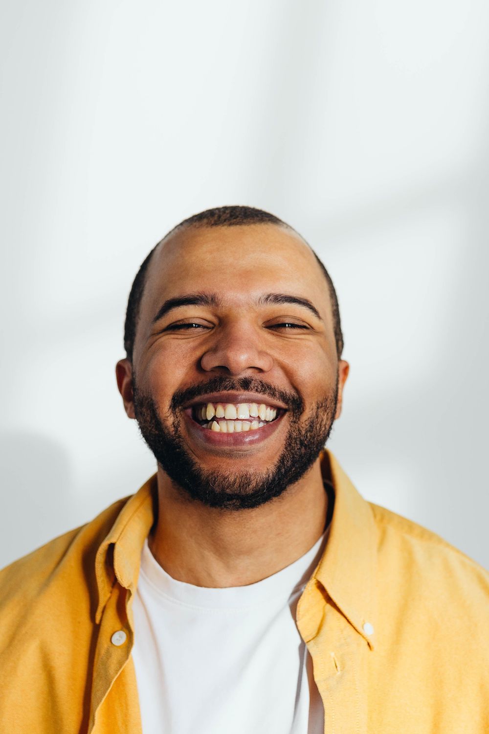 closeup of smiling young hispanic man with a beard and a yellow shirt