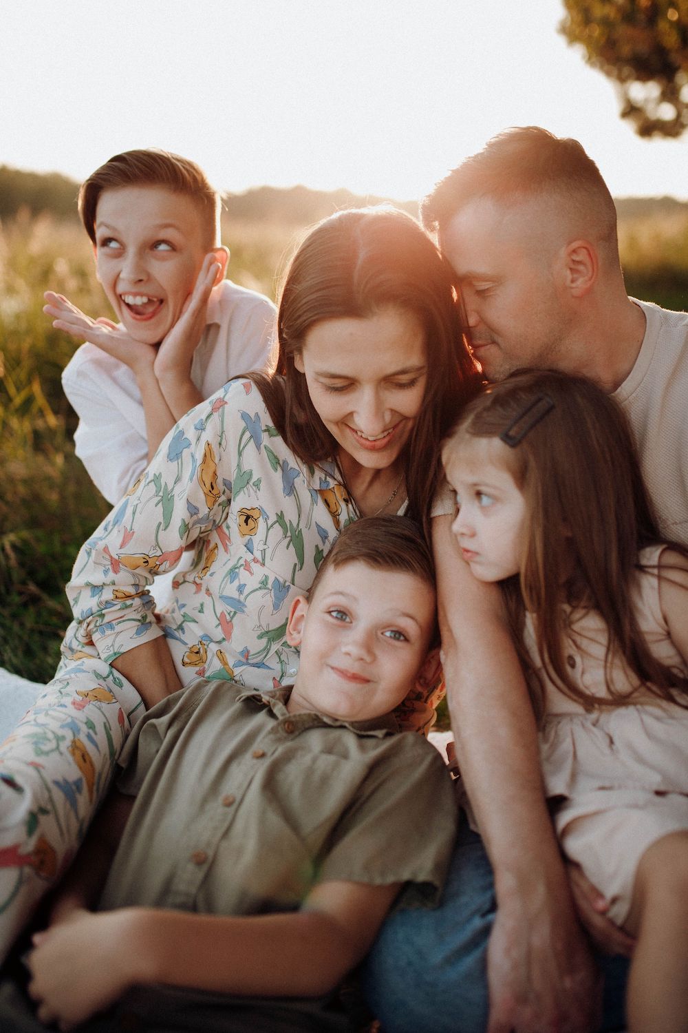 Parents and their 3 young children cuddled together in the grass