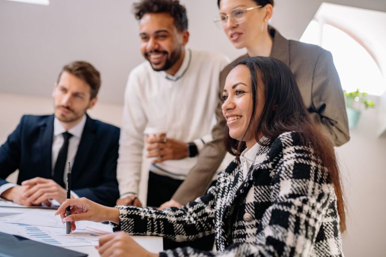 Office people looking at computer, with hispanic woman in the forefront with checked coat