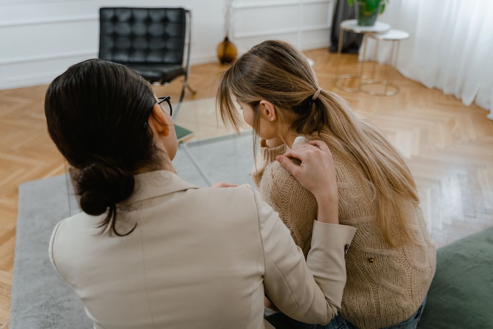 Therapist comforting a client, viewed from the back