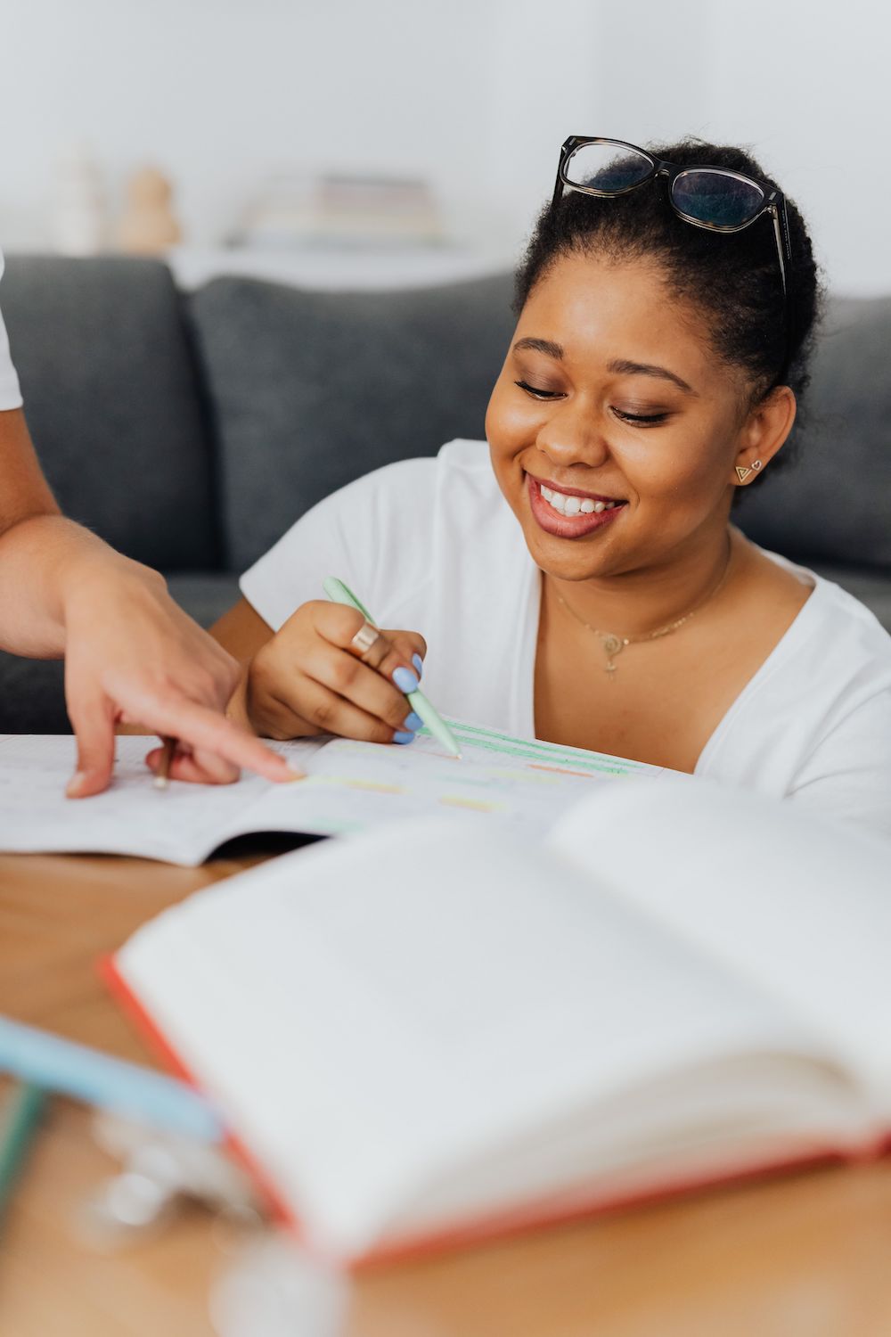 Young black adult student reviews her notes, looking at desk and smiling.