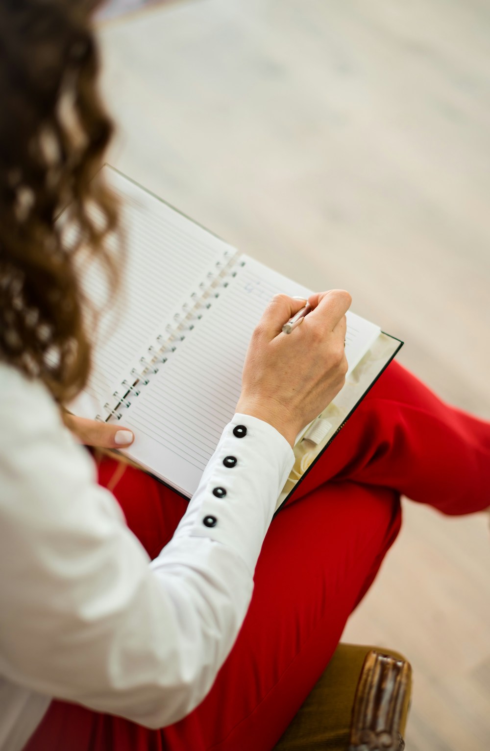 Top view of woman wearing red pants writing on a notebook