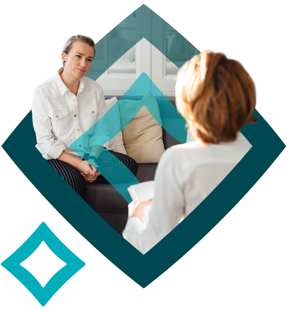 Vignette of Oak logo with 2 women facing each other during a counselling session, one with her back tu the viewer. Both wearing white shirts